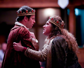 Margaret grips Henry's arms as she lectures him, he pensively looking back with his hands folded with insecurity at his breast, he in red velvet cloak, she in purple cloak, both with gold crowns sporting red rubies.