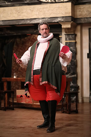 Production photo of Falstaff holding two halves of a red paper heart