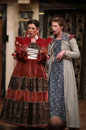 Production photo of Alice Ford and Margaret Page looking at the notes from Falstaff, each opened to form a full heart.